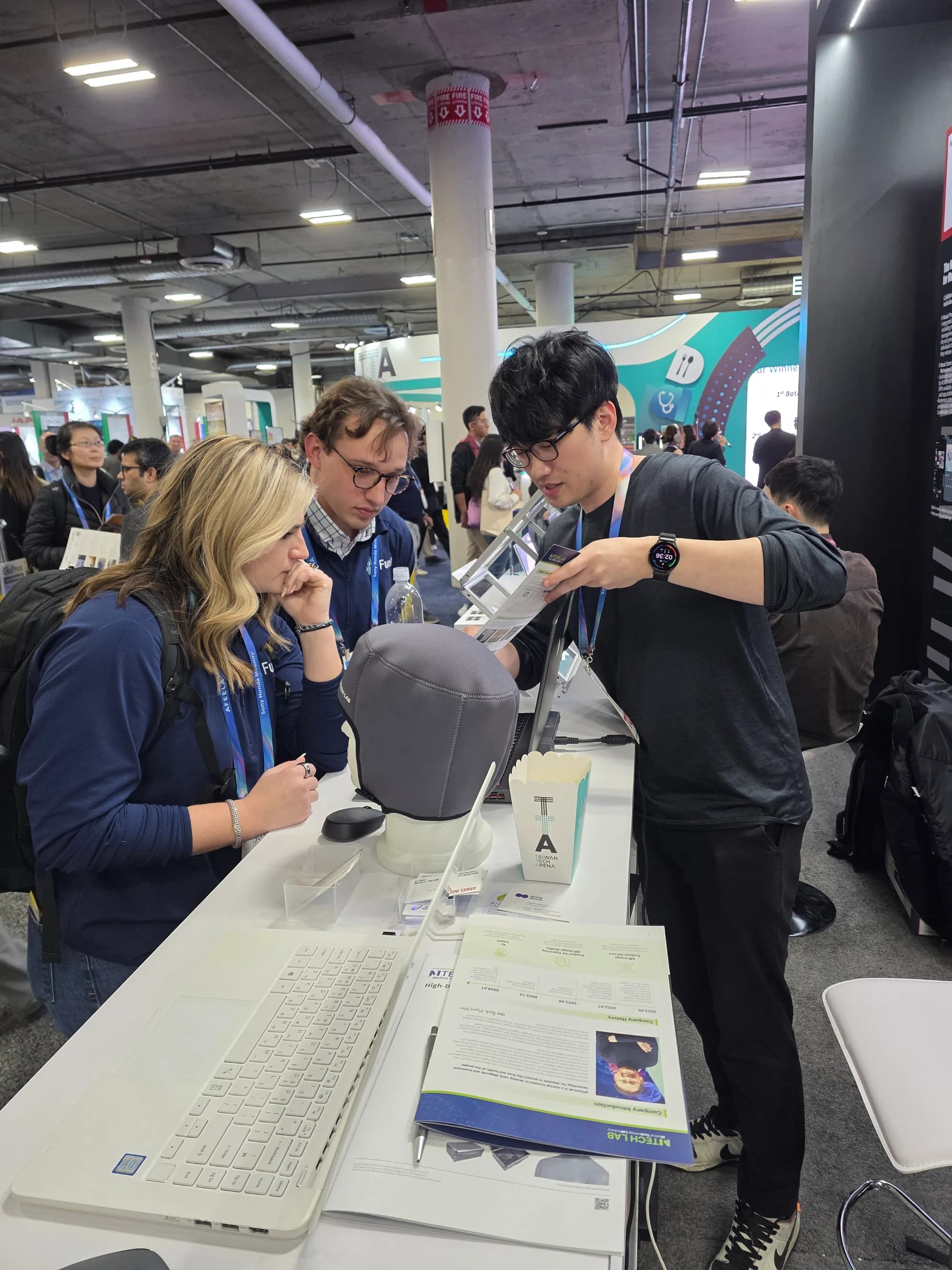 Visitor and MTechLab representative discussing a head MRI dielectric pad displayed on a mannequin