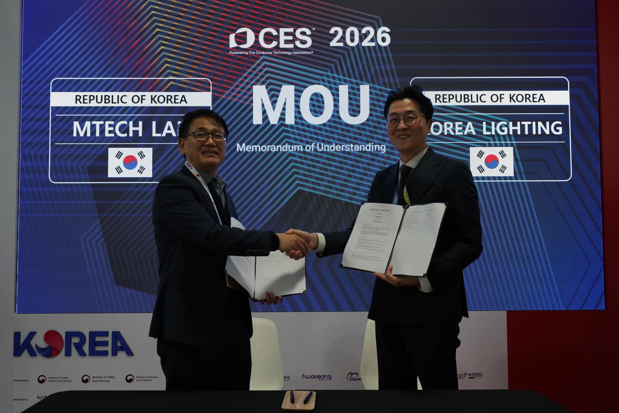 MTechLab and Korea Lighting representatives shaking hands while presenting the signed memorandum of understanding
