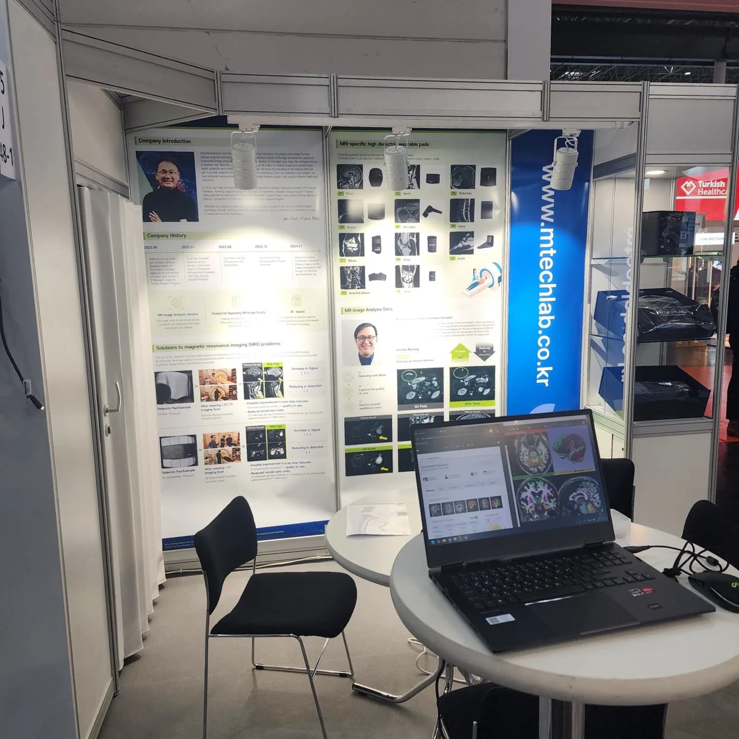MTechLab MEDICA 2024 booth product display with MRI pad mannequins, laptop, and monitor