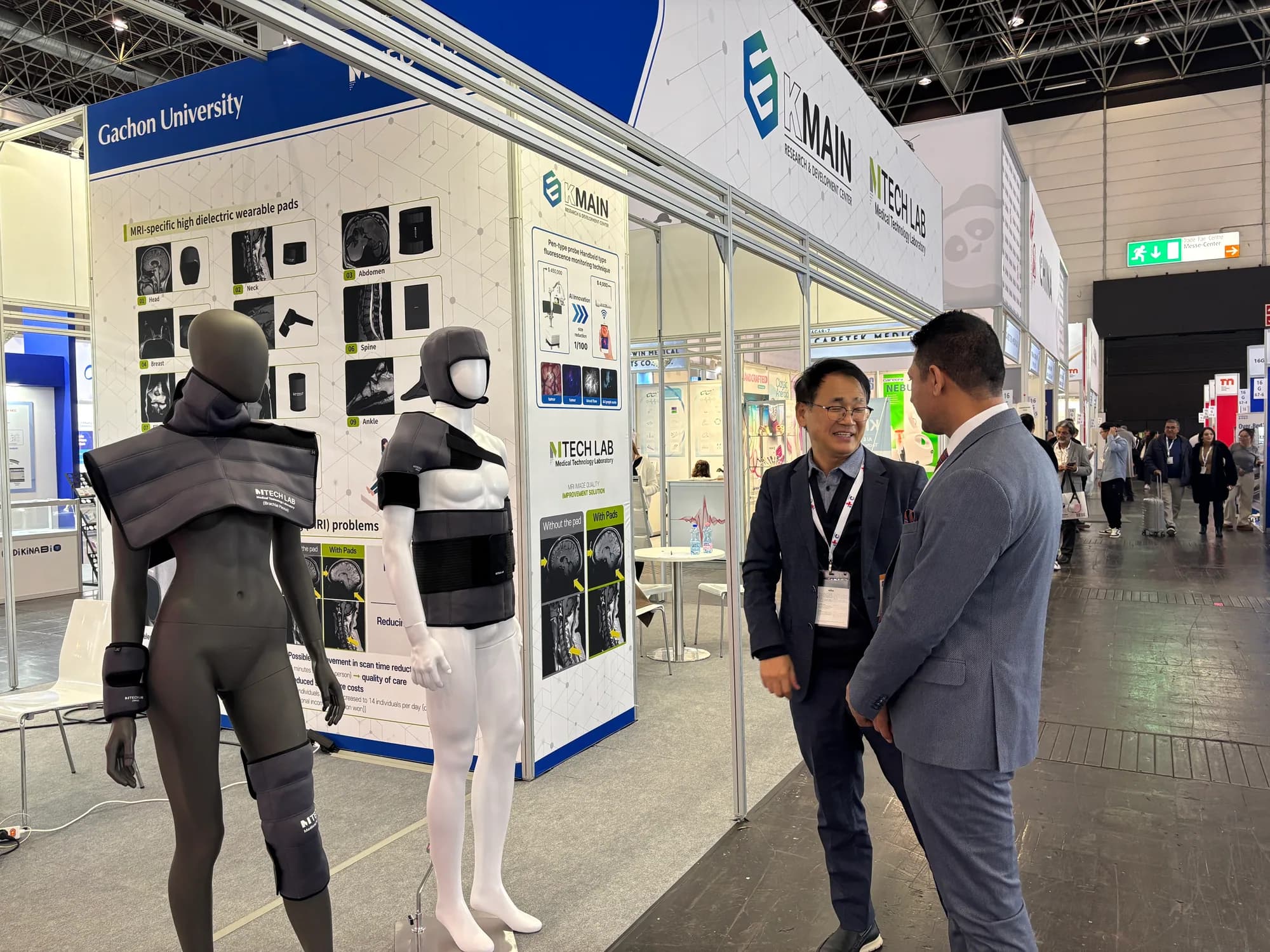 MTechLab representative presenting the MRI technology display wall to a visitor