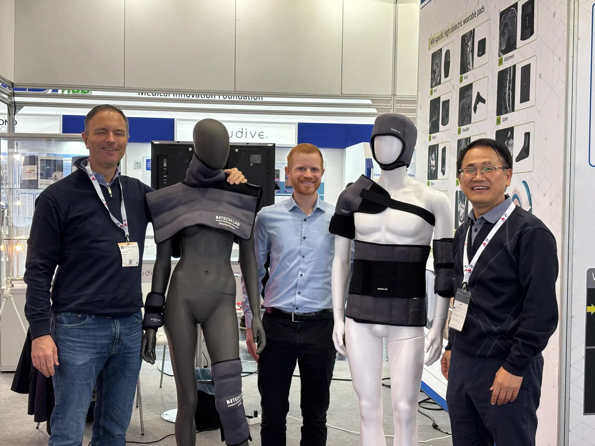 MEDICA 2025 visitor beside MRI pad mannequins and an MTechLab representative